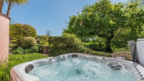 A hot tub surrounded by lush greenery and a stone wall.