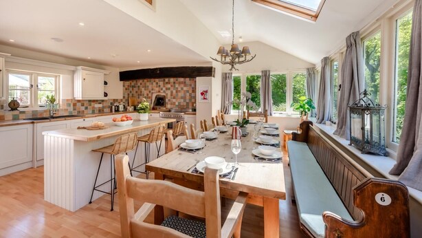 A spacious kitchen with a central island, large windows, and a dining area with a bench.