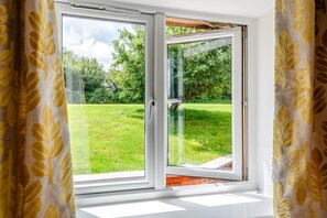 A room with a large sliding glass door leading to a grassy outdoor area.