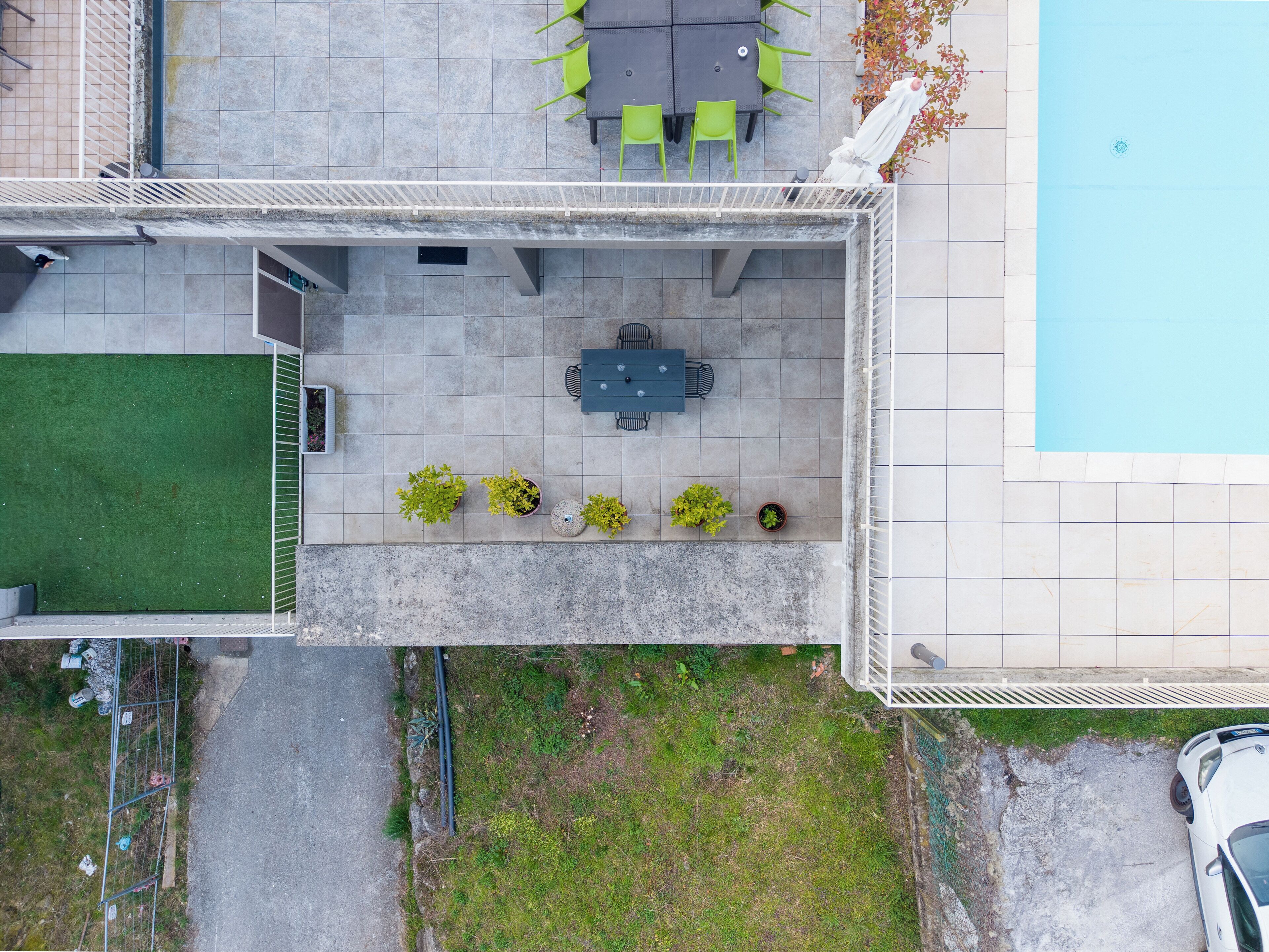 An aerial view of a rooftop patio with a table and chairs, surrounded by potted plants.