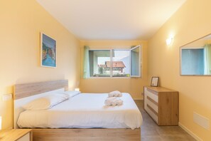 Ein Schlafzimmer mit Bett, Kommode, einem Gemälde und einem Fenster mit Blick.