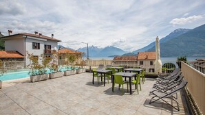 Eine Dachterrasse mit Pool, Sitzgelegenheiten im Freien und Blick auf die Berge.