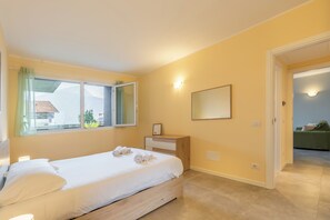 A bedroom with a bed, a bedside table, a mirror, and a window with curtains. - Larius Apartment-Residence with Pool on Lake Como (Musso)
