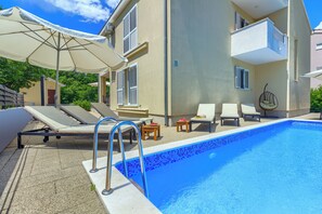 Ein Poolbereich mit Liegestühlen, Sonnenschirm und einem kleinen Tisch.
