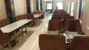 A spacious dining area with multiple tables and booths, featuring a modern design with marble and wood accents. - Hotel Grand Empire (Agra)