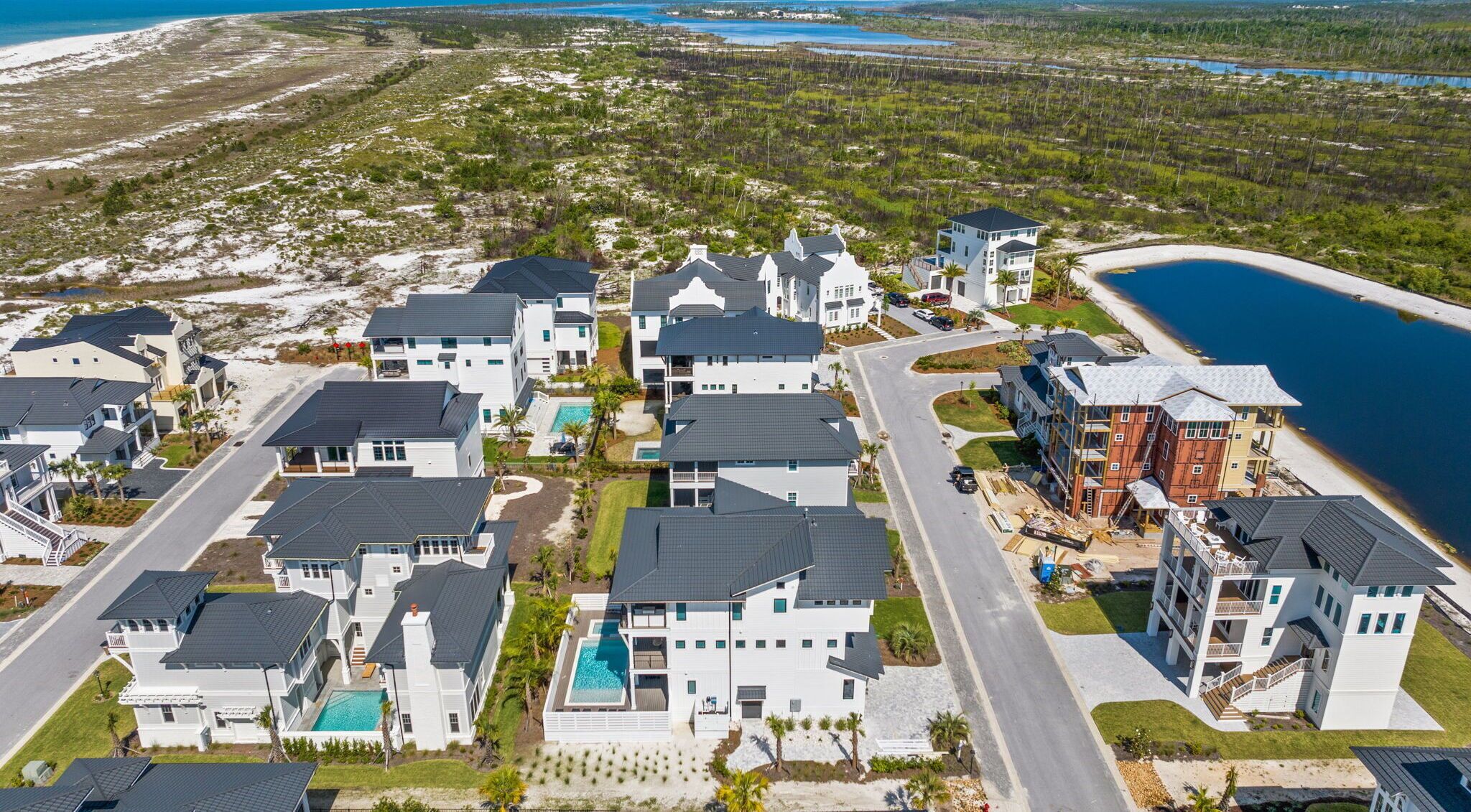 A coastal residential area with modern houses, a swimming pool, and a view of the ocean.