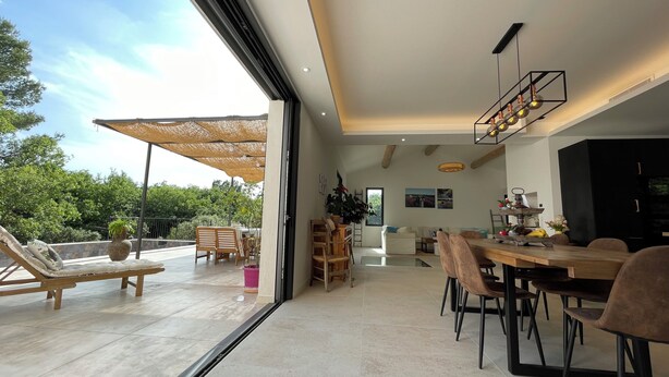 A spacious living area with a dining table, chairs, and a large window overlooking greenery. - Villa in Ménerbes in the Luberon golden triangle (Ménerbes)