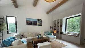 A spacious living room with a white sofa set, a wooden coffee table, and a large window offering a view of trees. - Villa in Ménerbes in the Luberon golden triangle (Ménerbes)
