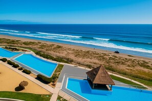 A resort with multiple swimming pools, a beach, and ocean views.