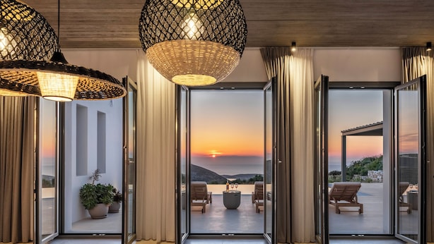 Ein modernes Interieur mit einer Glastür, die auf einen Balkon mit Sonnenuntergangsblick führt.