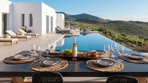 Ein Essbereich mit Blick auf einen Pool, Sitzgelegenheiten im Freien und einem gedeckten Tisch.