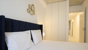 Une chambre d’hôtel avec un lit, du linge de lit blanc, une tête de lit sombre et un élément décoratif fixé au mur.