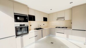 Eine moderne Küche mit weißen Schränken, einem Backofen, einer Mikrowelle und einem Gasherd.