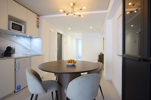 A modern kitchen with a microwave, a sink, and a round dining table with chairs. - FLH Porto Central Apartment III (Oporto)
