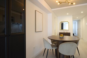 Un comedor moderno con una mesa redonda, dos sillas, un frutero y una obra de arte enmarcada en la pared.