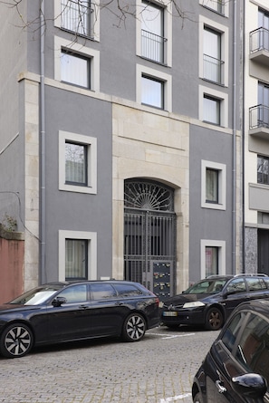 Ein mehrgeschossiges Gebäude mit moderner Fassade, das einen zentralen Bogen und zahlreiche Fenster aufweist.