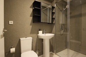 Een badkamer met toilet, wastafel en douche.