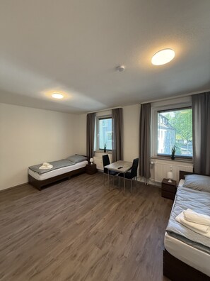 Habitació d'hotel senzilla amb un llit, un taulell petit i una cadira.