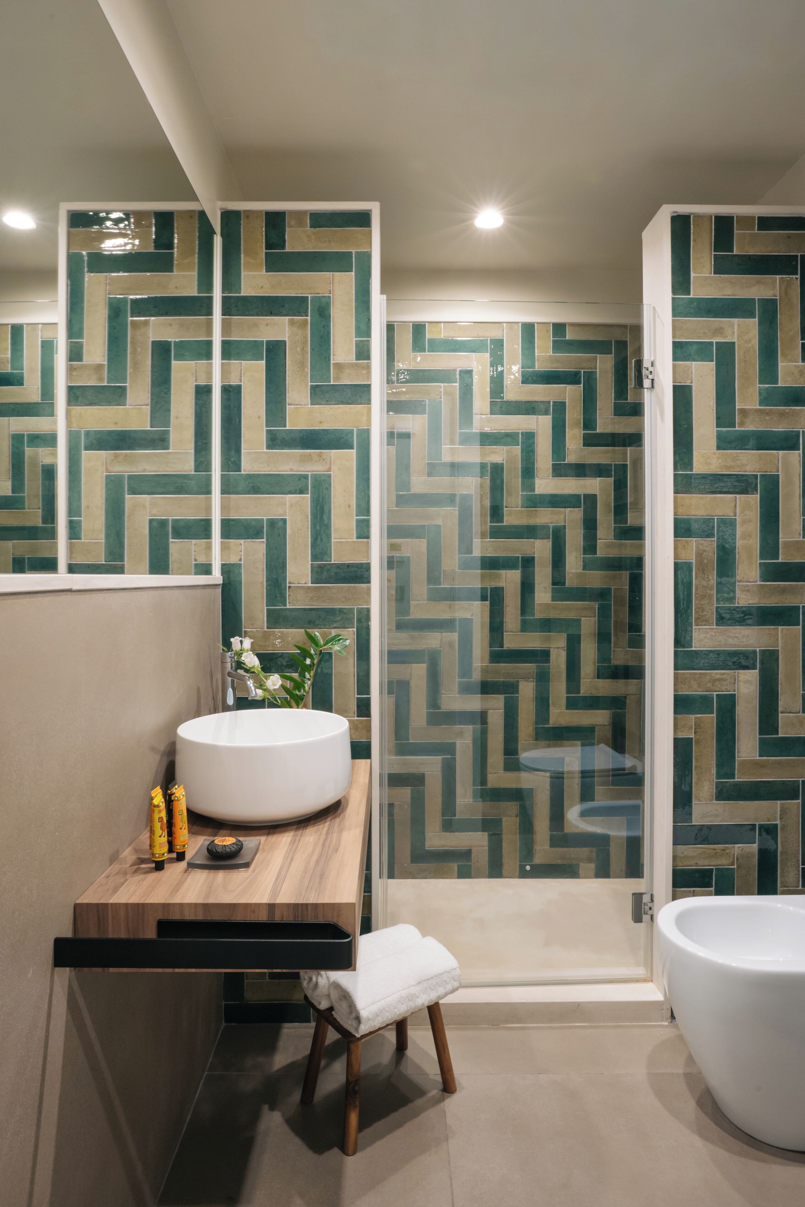 A modern bathroom with a large mirror, a wooden vanity, a white sink, a white bathtub, and a shower area.