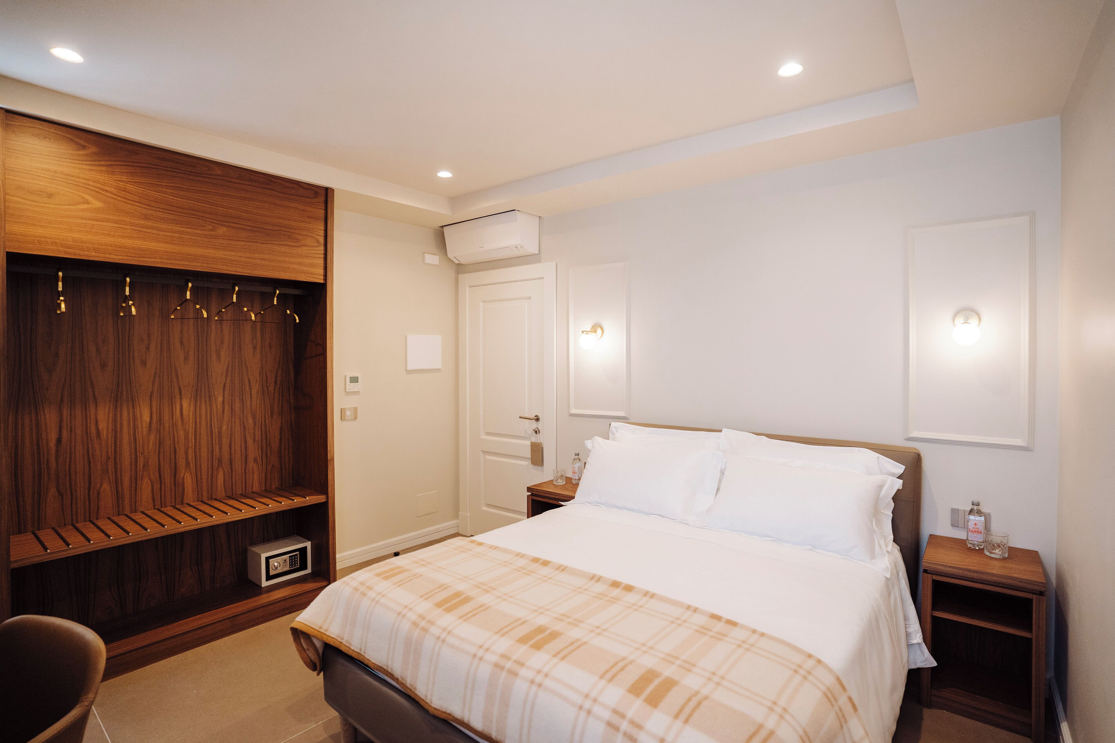 Ein Hotelzimmer mit einem Bett, einem Holzschrank, einem Nachttisch und einem Sessel.