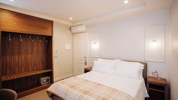 Ein Hotelzimmer mit einem Bett, einem Holzschrank, einem Nachttisch und einem Sessel.