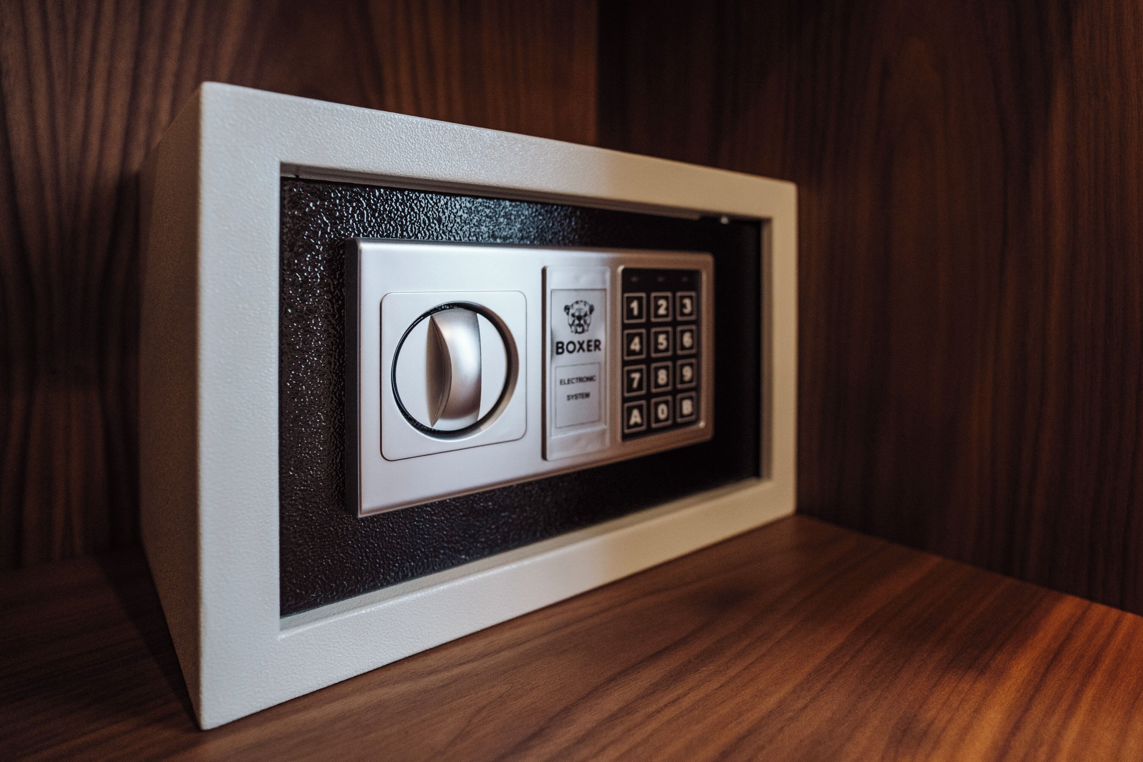 Una cassaforte con quadrante numerico e tastierino, inserita in un mobile in legno.