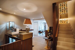 Un interior moderno con una mesa de recepción, una lámpara, una escalera y un área de comedor.