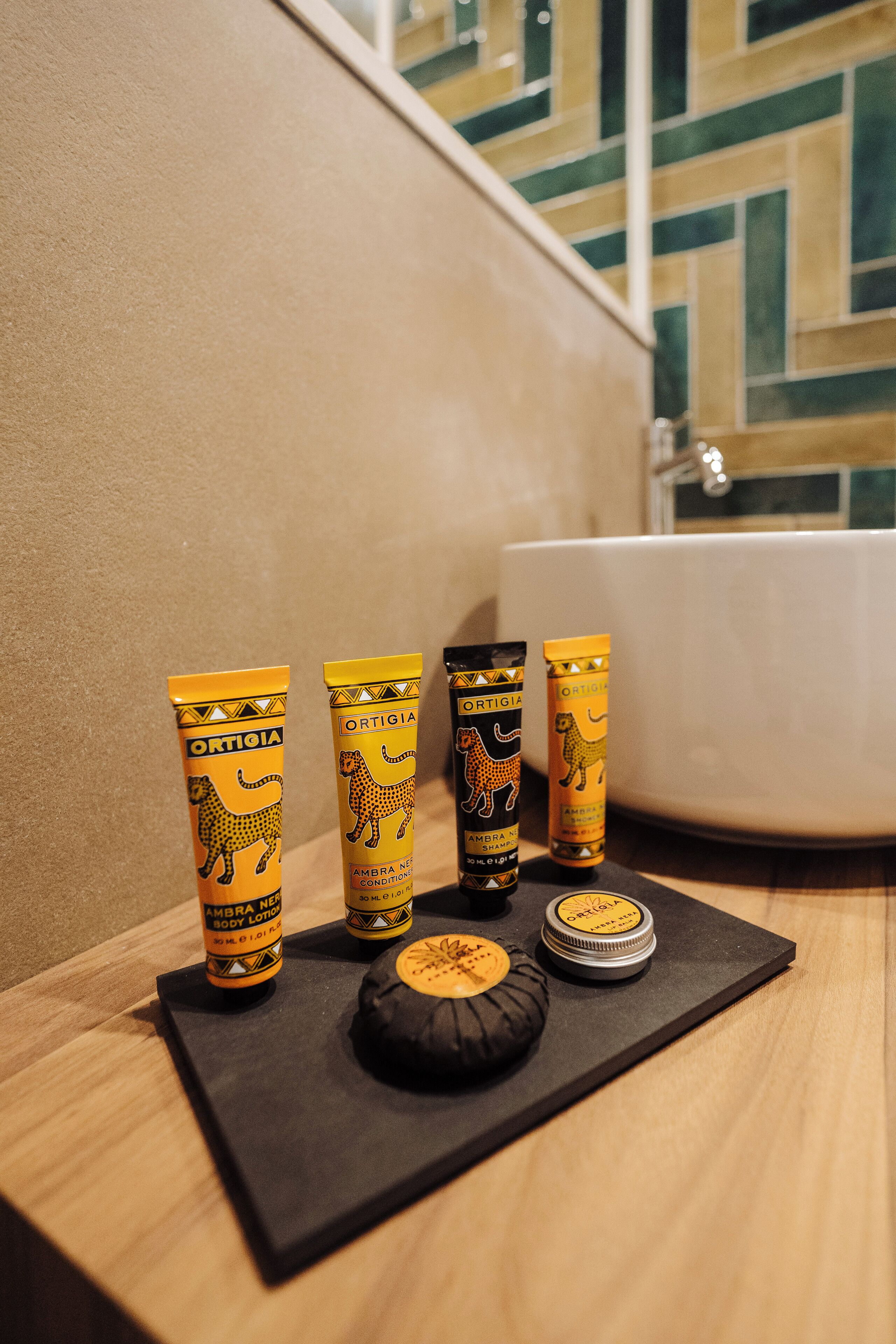 A bathroom with a black mat on the floor, a bathtub, and four toiletries with leopard designs.