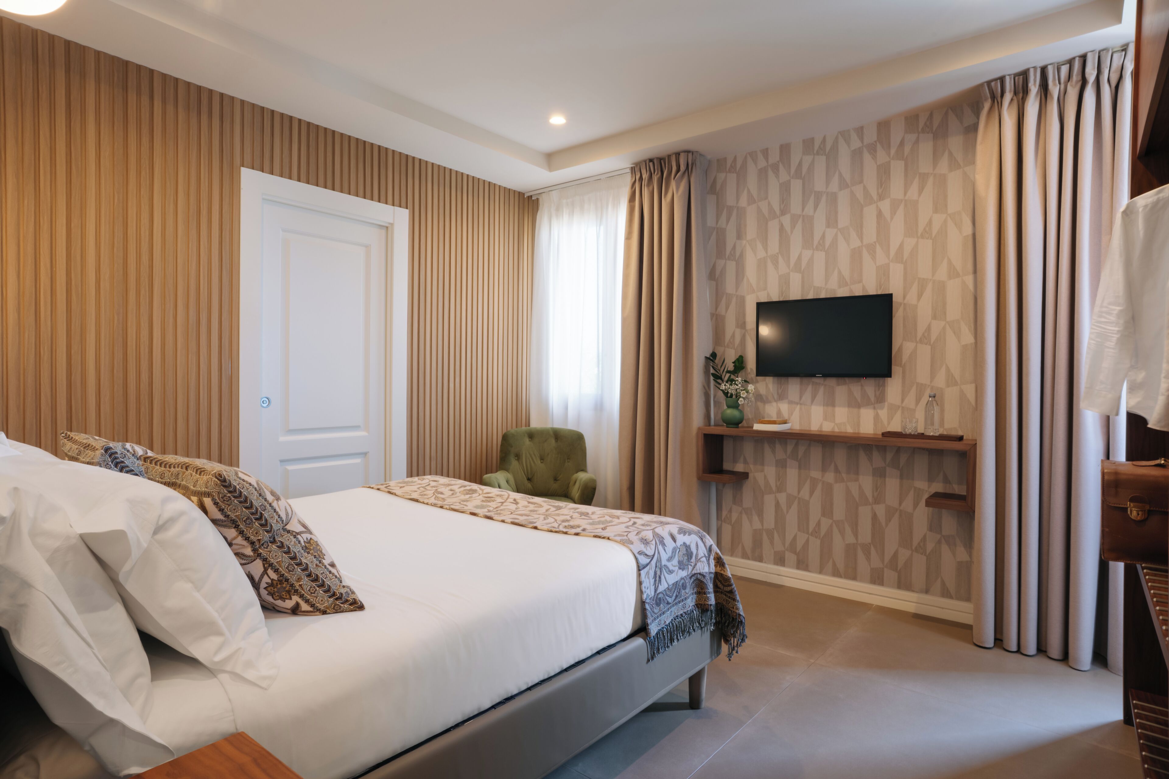 A bedroom with a bed, a television, a chair, and a shelf.