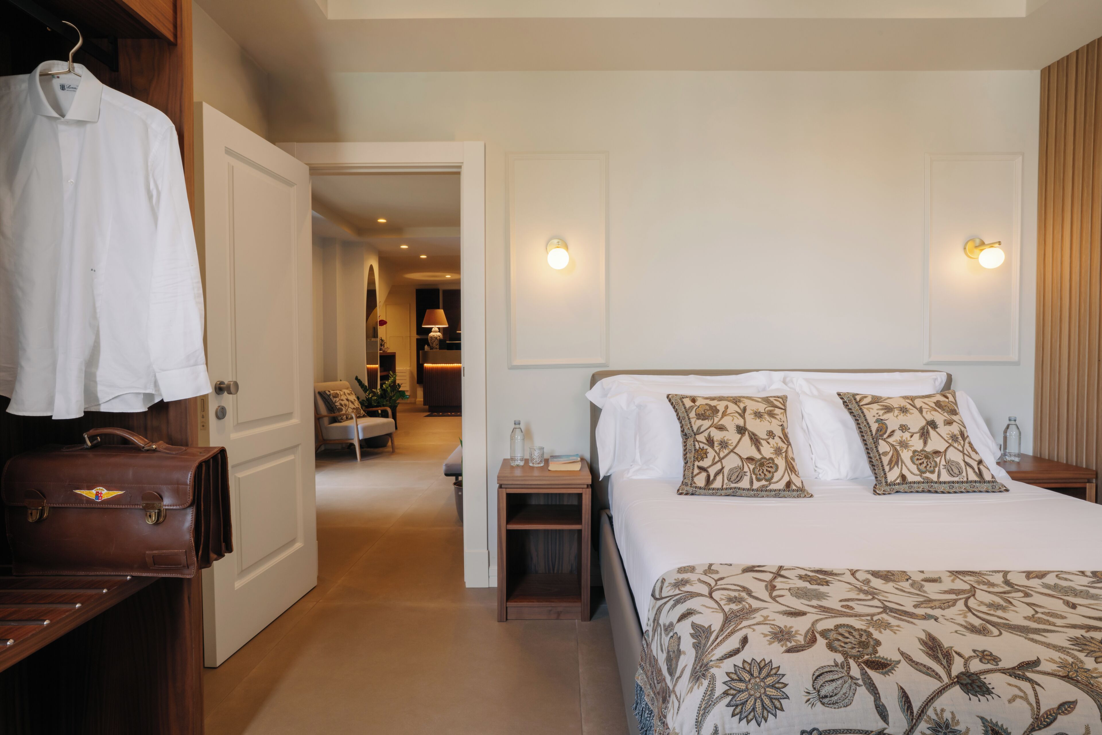 Un dormitorio con cama, mesitas de noche, armario y puerta que da a otra habitación.