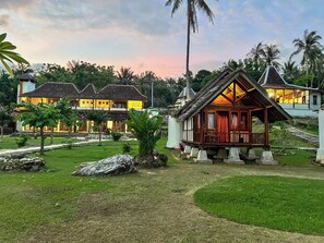 A resort with multiple buildings, including a prominent wooden structure with a balcony, surrounded by lush greenery and palm trees. - Arys Lagoon Resort Karimunjawa (Karimunjawa)