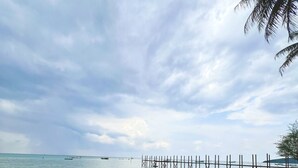 A beach with clear turquoise water, a wooden pier extending into the sea, and a palm tree on the right. - Arys Lagoon Resort Karimunjawa (Karimunjawa)