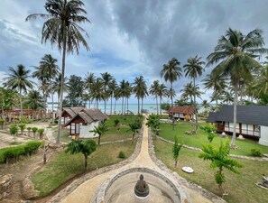 Un resort con un camino central que lleva a una estatua, rodeado de palmeras y edificios bajos.