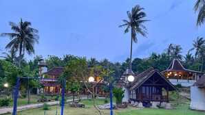 A tropical resort with a swing set, a small hut, and traditional buildings with thatched roofs. - Arys Lagoon Resort Karimunjawa (Karimunjawa)