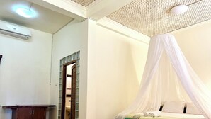 A bedroom with a bed under a canopy, a wooden cabinet, and a tiled floor. - Arys Lagoon Resort Karimunjawa (Karimunjawa)