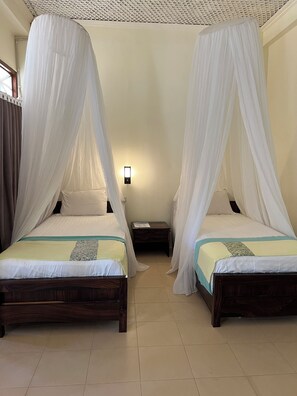 Two beds with canopy beds, a nightstand, and a wall-mounted light fixture. - Arys Lagoon Resort Karimunjawa (Karimunjawa)