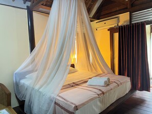 A bed with a canopy, a bedside table, and a wall-mounted air conditioning unit. - Arys Lagoon Resort Karimunjawa (Karimunjawa)