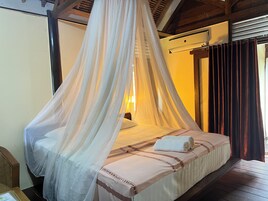 Una cama con dosel, una mesita de noche y un aire acondicionado instalado en la pared.
