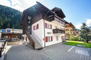 Un edificio a due piani con facciata in legno, persiane rosse e un balcone.