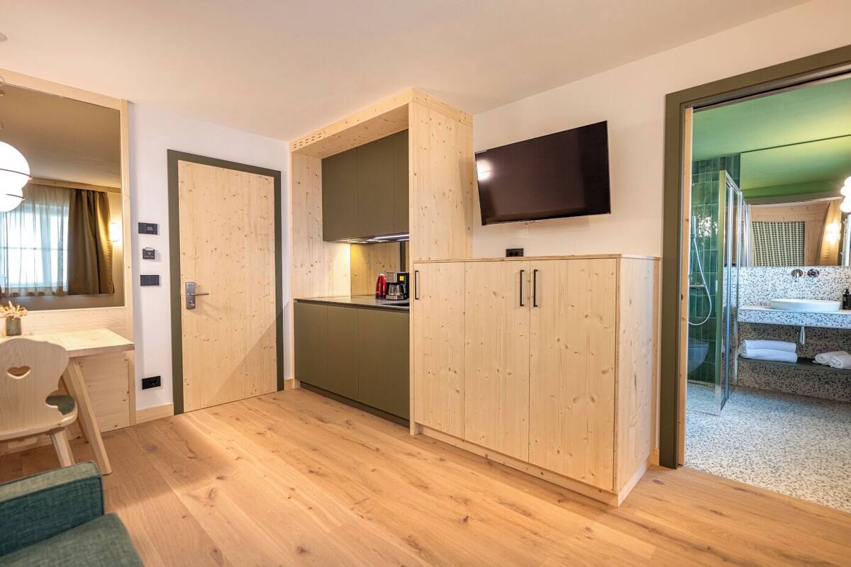 Une pièce compacte comprenant un coin cuisine, un espace repas et une salle de bain avec douche.