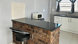A kitchen with a microwave, a sink, and a bar counter. - Silalise Lodge (Greater Tubatse)