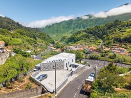 Un barrio residencial con un edificio de piedra, una calle pavimentada y montañas al fondo.