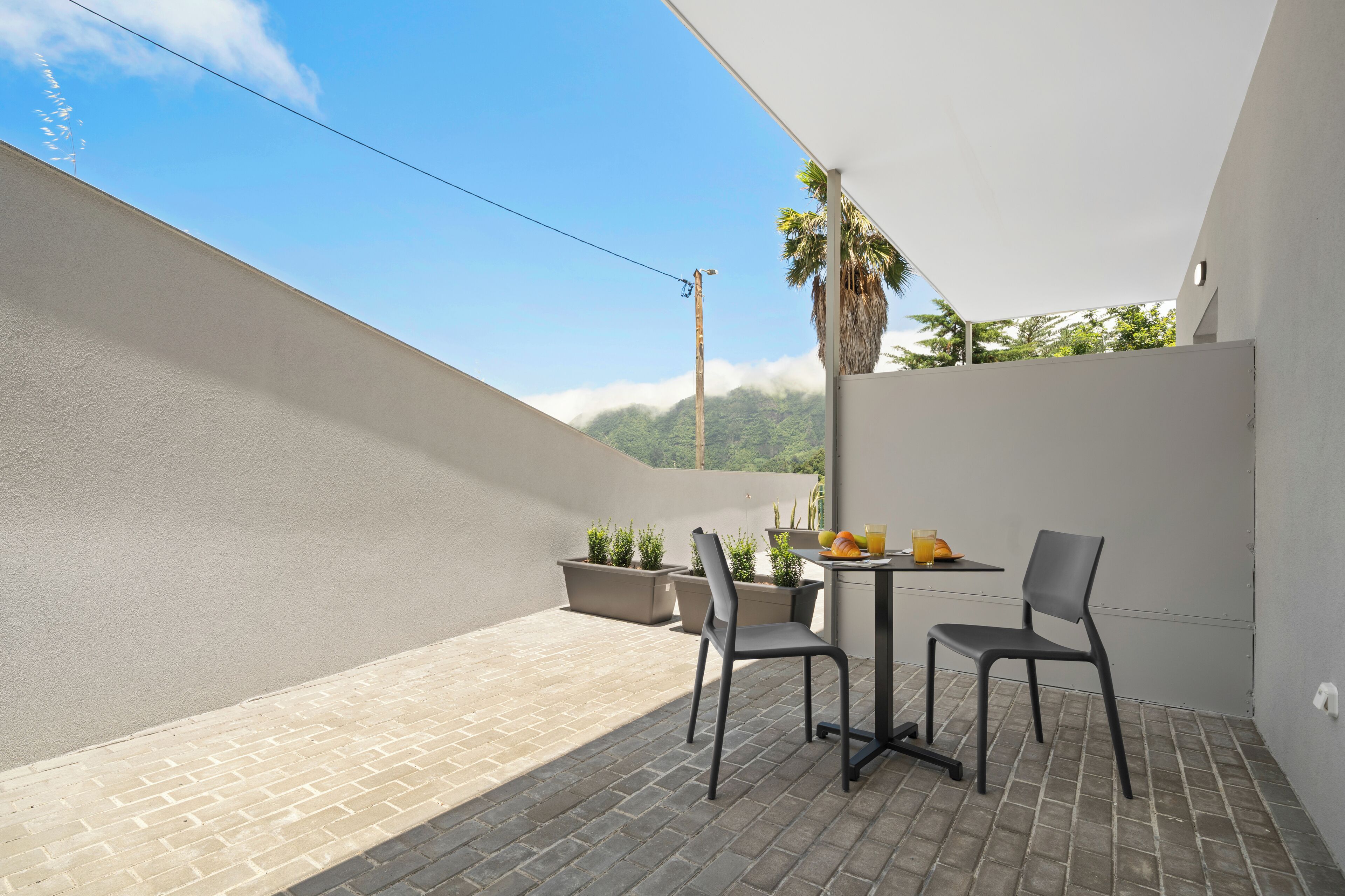 A balcony with two chairs, a table, and potted plants.