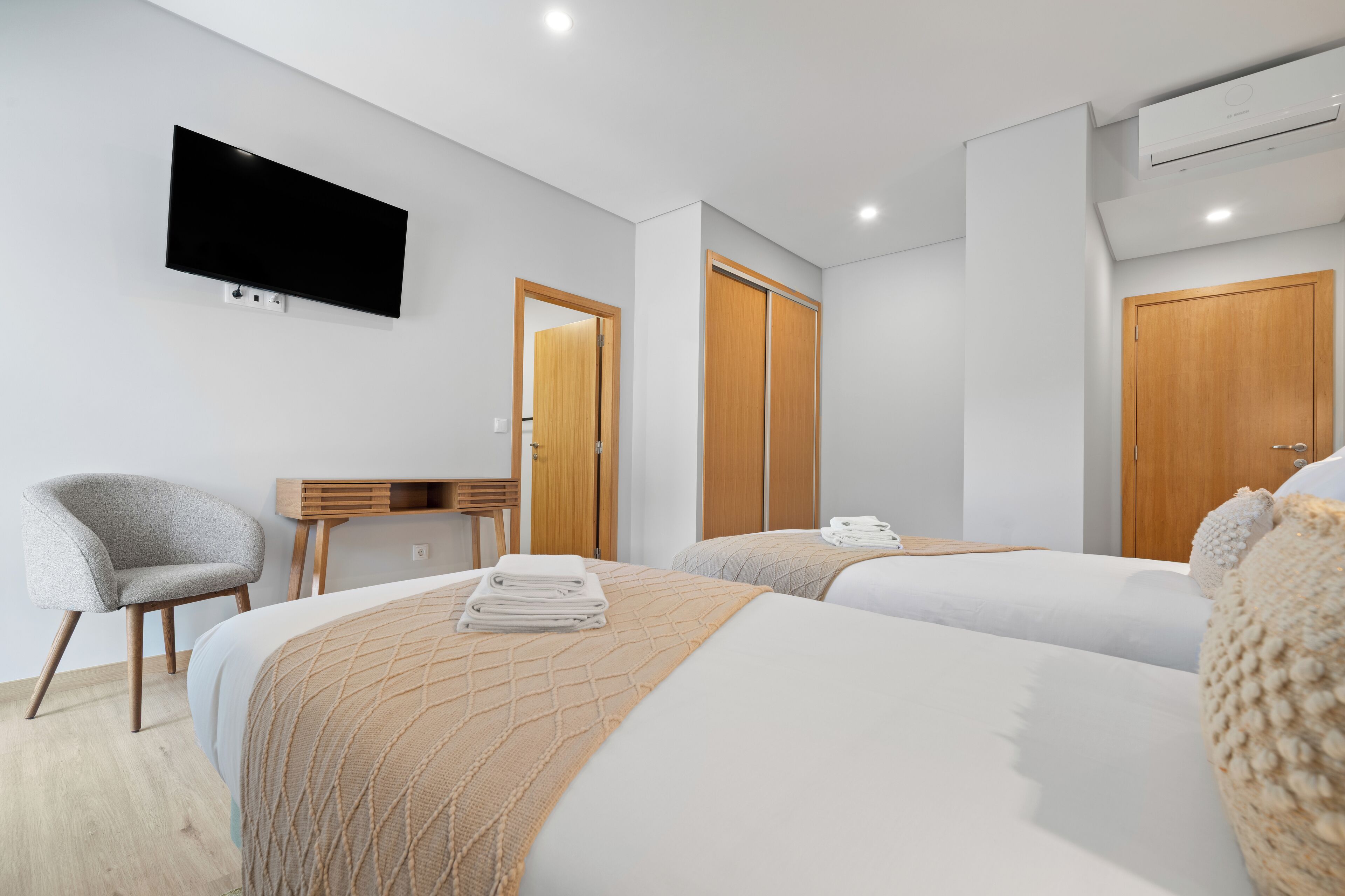 Une chambre d’hôtel moderne équipée de deux lits, d’un téléviseur à écran plat fixé au mur, d’un bureau et d’une chaise.
