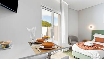 Una habitación de hotel moderna con cama, mesita de noche y zona de comedor con mesa para dos.