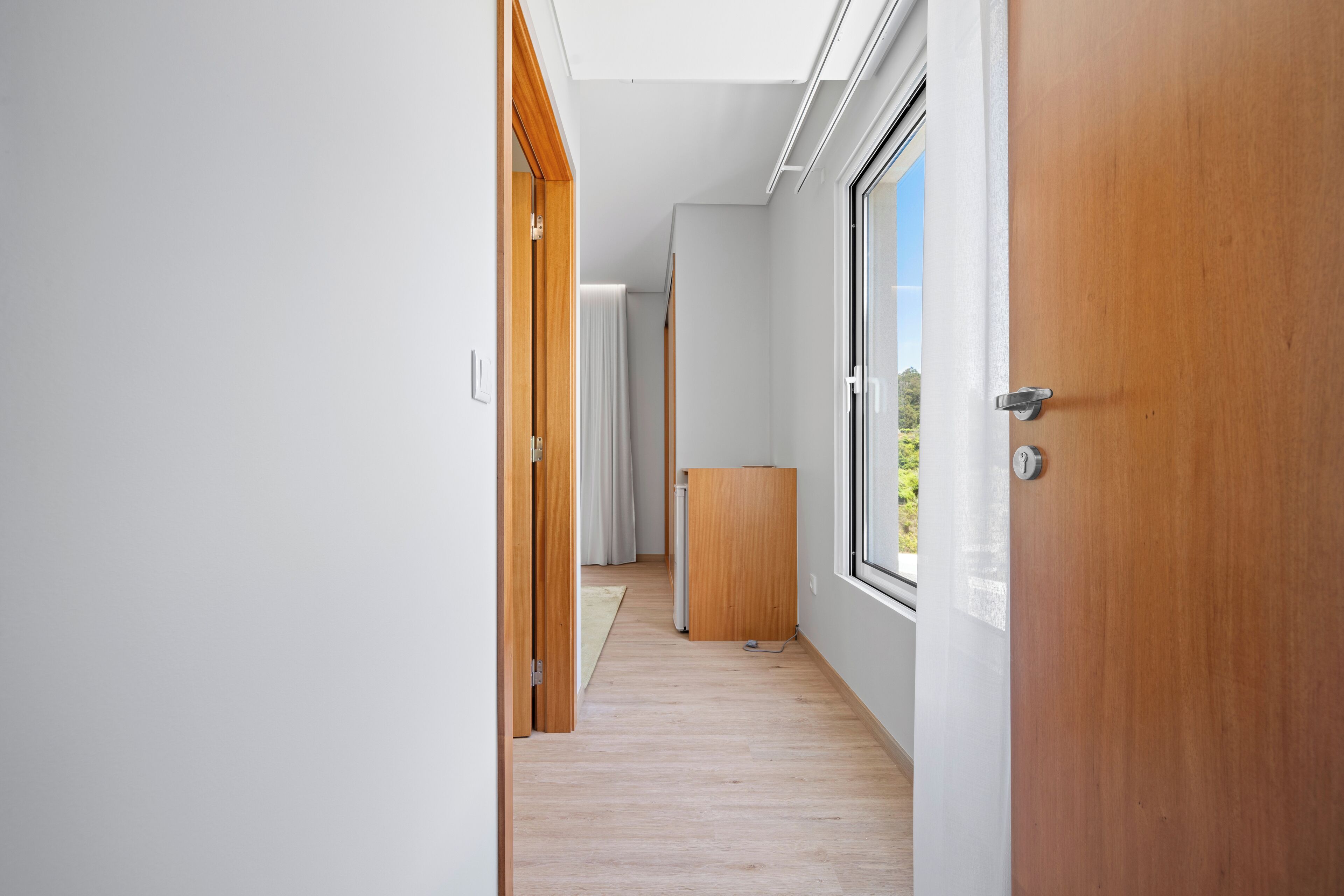 A hallway with wooden doors, a window, and a radiator.