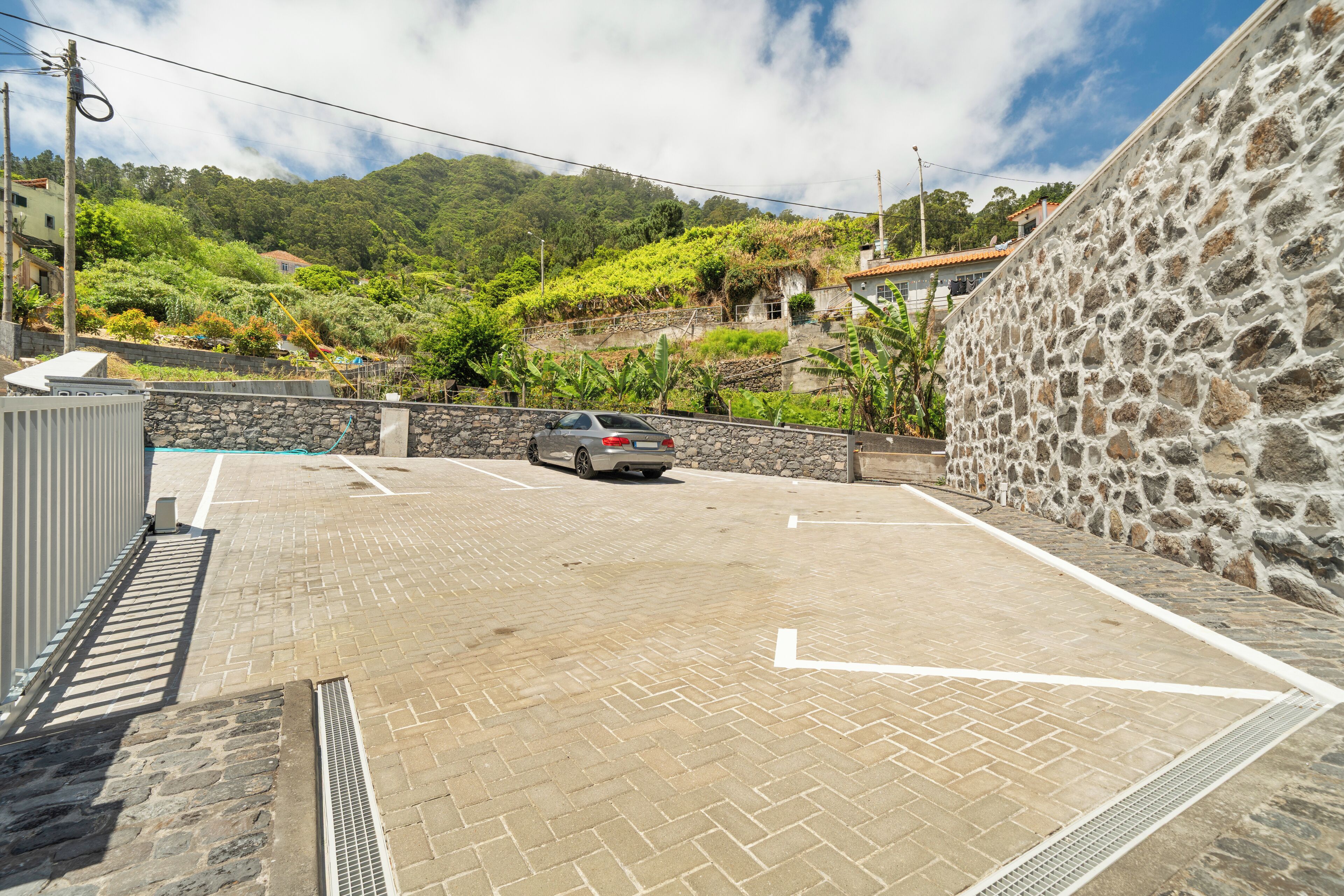 A parking area with a stone wall and a car parked in the distance.