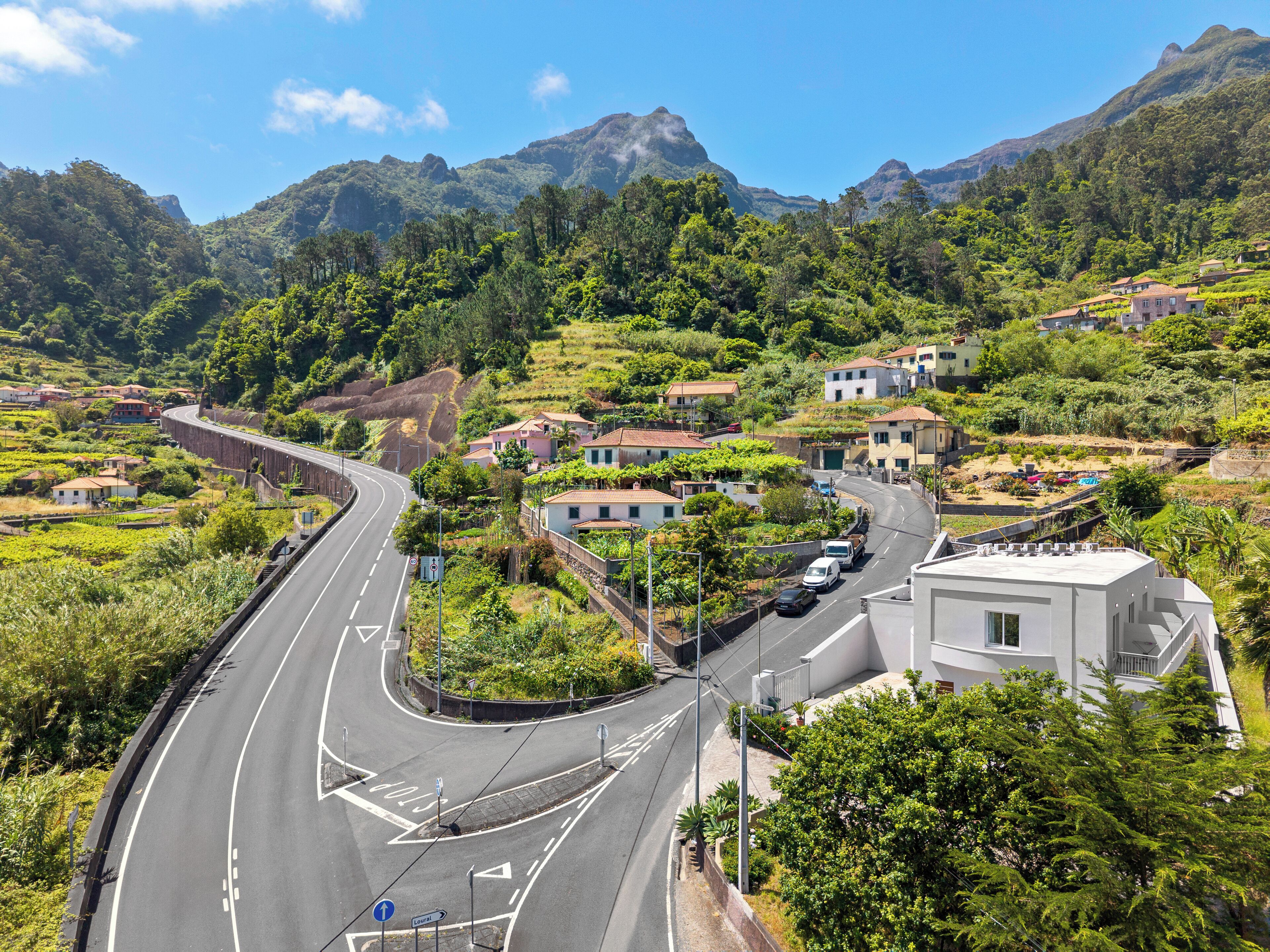 Una carretera serpenteante a través de una zona montañosa con casas y vegetación.