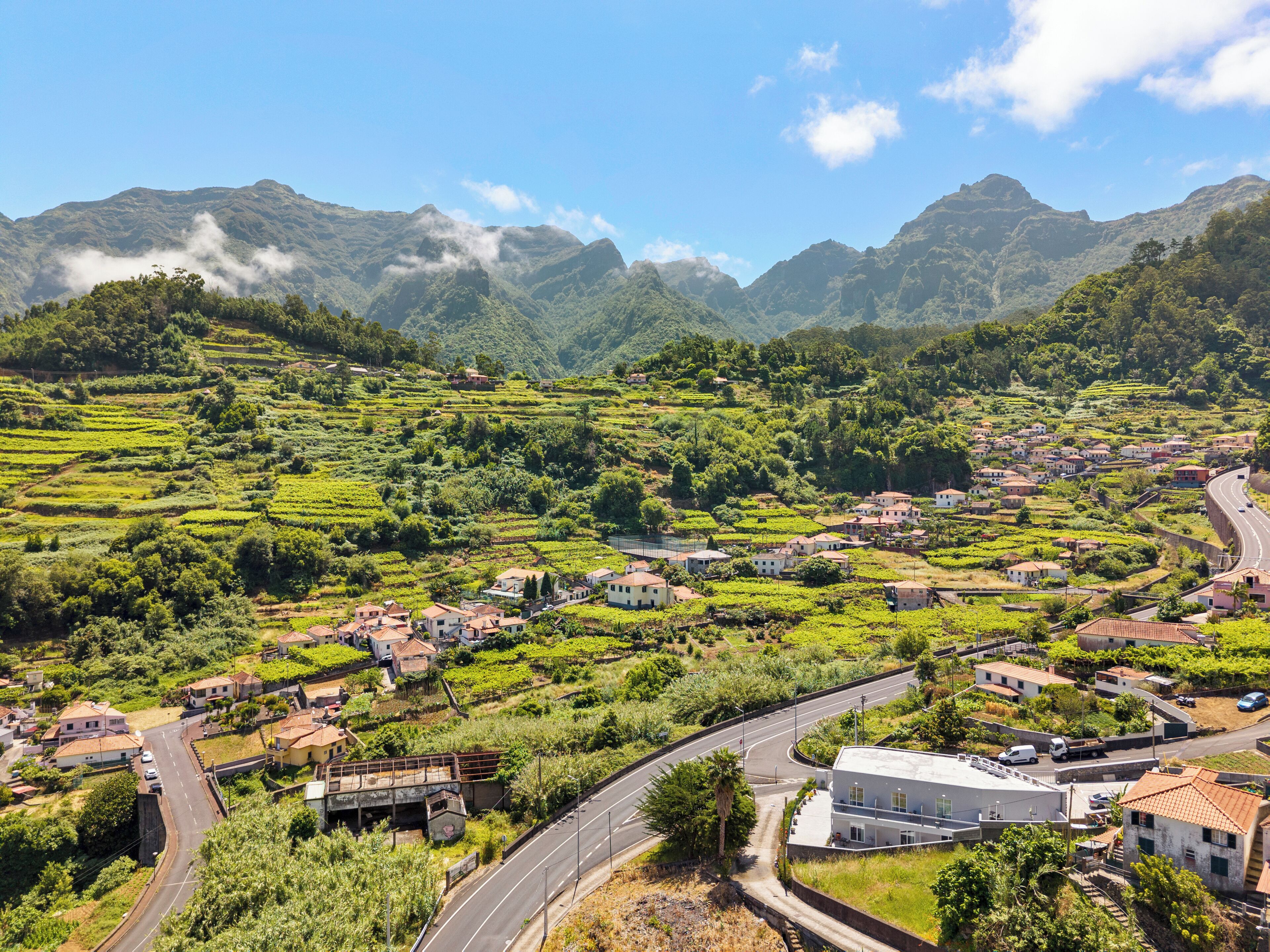 Un village rural avec des champs en terrasses, des maisons et une route sinueuse.