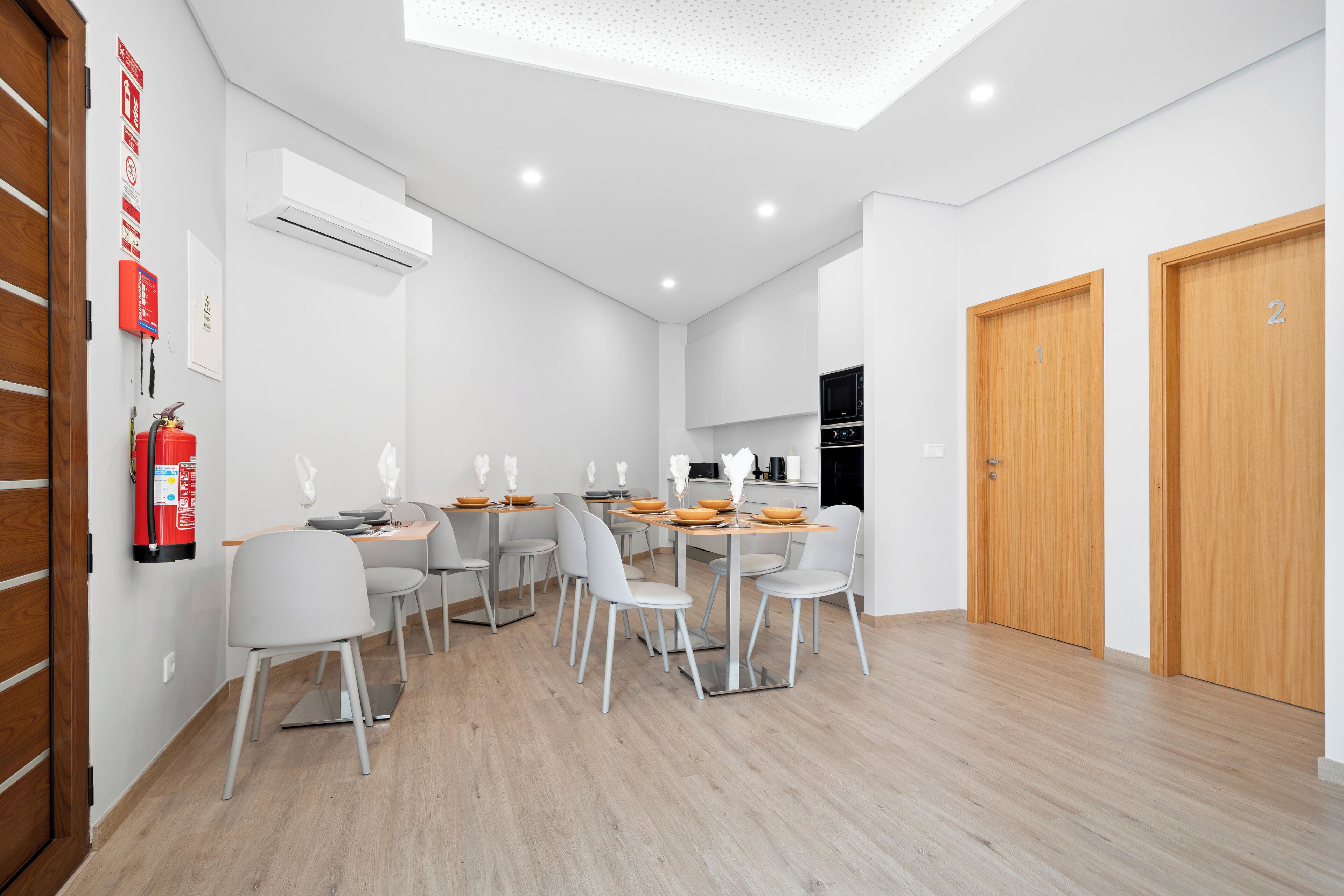 A modern dining area with a high ceiling, recessed lighting, and a central table with chairs.